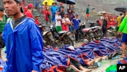 People gather near the bodies of victims of a landslide near a jade mining area in Hpakant, Kachine state, northern Myanmar Thursday, July 2, 2020. 