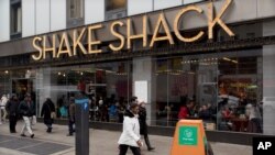 FILE - People walk past a Shake Shack restaurant, in New York. 