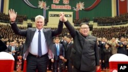 En esta fotografía del domingo 4 de noviembre de 2018 publicada por el gobierno norcoreano, el presidente cubano Miguel Díaz-Canel, izquierda, y el líder norcoreano Kim Jong Un elevan sus manos unidas durante una ceremonia de bienvenida al gobernante caribeño, en Pyongyang, Corea del Norte.