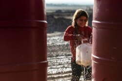 A Syrian girl fills a jug with water in Washukanni camp, on Dec. 16, 2019, which was recently established on the outskirts of Hasakeh city for people displaced from the northeastern Syrian town of Ras Al-Ain.