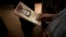 A customer holds a stack of 100-bolivar notes at a bakery in downtown Caracas, Venezuela, Dec. 12, 2016. Venezuelans were rushing to spend their 100-bolivar notes after a surprise announcement that they will be taken out of circulation. More of the new 500-bolivar notes arrived in Venezuela, Dec. 28, 2016. 