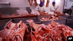 FILE - Butchers prepare cuts of meat at Smithfield Market, in London, England, July 18, 2016. A shortage of carbon dioxide is hitting British food processing companies who rely on the gas to stun animals before slaughter and to vacuum pack food.