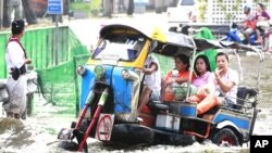 ປະຊາຊົນບາງຄົນໃຊ້ລົດ "tuk-tuk,"ເປັນພາຫະນະແລ່ນຜ່ານນໍ້າຖ້ວມຖະ
ໜົນສາຍນຶ່ງທີ່ຖືກນໍ້າຖ້ວມໃນບາງກອກ
ວັນທີ 7 ພະຈິກ 2011.