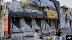 Abdul Basr, 45, center, chats with his neighbor as he sits in front of his damaged pizzeria on Tripoli street in Misrata, Libya, September 2, 2011.