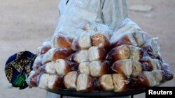 A boy sells bread near a court where youths play Eton fives game in a court in Katsina.