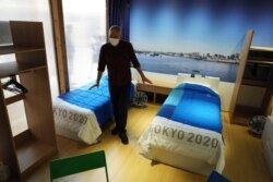 A journalist looks at cardboard beds, for the Tokyo 2020 Olympic and Paralympic Villages, which are shown in a display room the Village Plaza, June 20, 2021, in Tokyo.
