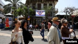 Луѓе поминуваат покрај израелското знаме, во Тел Авив