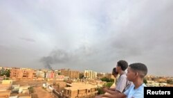 FILE - People watch as smoke rises during clashes between the army and the paramilitary Rapid Support Forces (RSF), in Omdurman, Sudan July 4, 2023. 