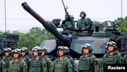 资料照片：在台湾举行的实弹演习中，士兵们在一辆美国制造的M1A2T“艾布拉姆斯”主战坦克前合影留念。(2025年7月10日)