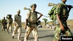 Eritrean soldiers march past displaced civilians as they redeploy near the town of Adi Quala on June 2.