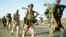 Eritrean soldiers march past displaced civilians as they redeploy near the town of Adi Quala on June 2.