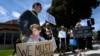 FILE - This April 28, 2019, file photo shows Kyle Fox holding a sign with his father Brady Fox in support of the victims of Chabad of Poway synagogue shooting in Poway, Calif. 