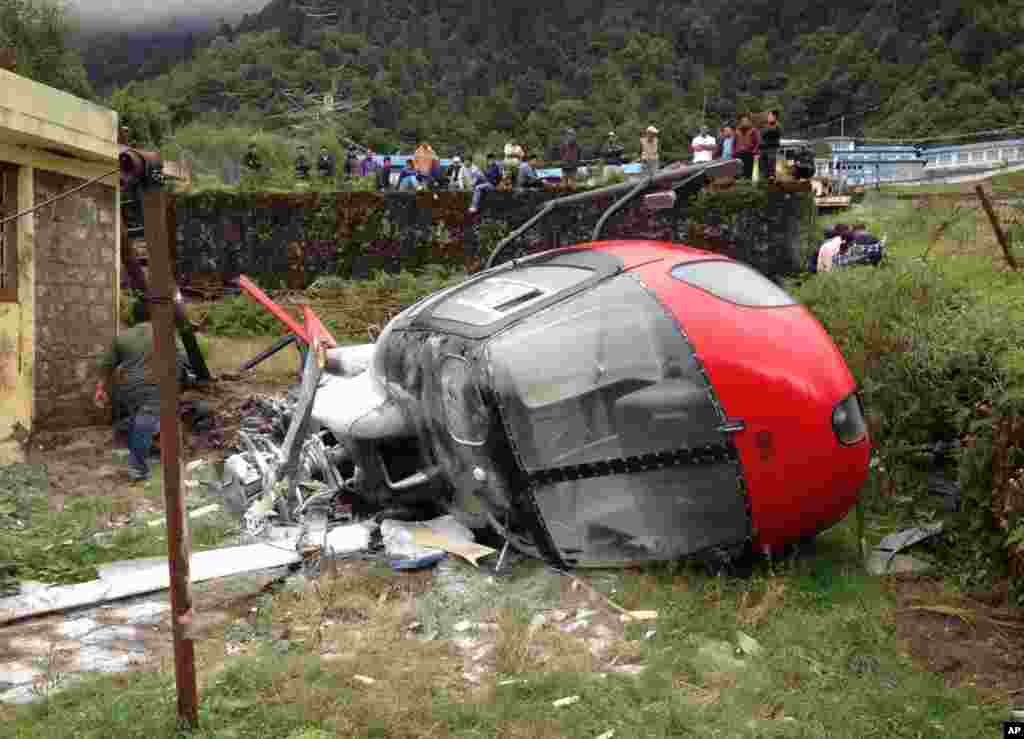 Warga Nepal melihat helikopter yang jatuh di desa Lukla, saat mencoba mendarat di dekat Gunung Everest, melukai ke-4 orang penumpangnya.