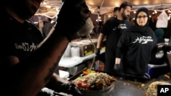 Ali el Romh dari Subs dan Shawarma Peepo sedang meramu masakan di Ramadhan Suhoor Festival di Dearborn Heights, Michigan, 18 Mei 2019 (Foto: AP / Carlos Osorio)