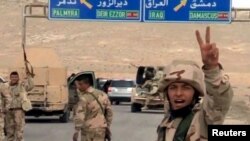 Forces loyal to Syria's President Bashar al-Assad gesture as they advance into the historic city of Palmyra in this picture provided by SANA, March 24, 2016.