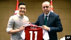 Turkey's President Recep Tayyip Erdogan, right, poses for a photo with Turkish-German Arsenal soccer player Mesut Ozil in London, May 13, 2018.