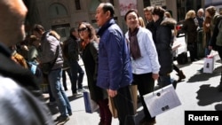 (FILE)Chinese shoppers stand with shopping bags on a sidewalk along 5th Avenue in New York City, April 4, 2013. Chinese tourists, known for traveling in organized tours and snapping up luxury fashion abroad, spent $102 billion on foreign trips last year, 