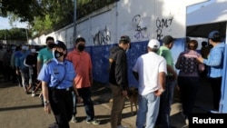 Una mujer policía pasa junto a personas que hacen cola para ingresar a una escuela utilizada como mesa de votación, durante las elecciones presidenciales, en Managua, Nicaragua, el 7 de noviembre de 2021. REUTERS 