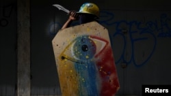 A demonstrator holding a rudimentary shield and a knife poses for a picture before a rally against Venezuelan President Nicolas Maduro's government. "I protest because the situation is very tough and we are going hungry. We really need a change." 