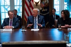 Bank CEOs Brian Moynihan (L) and Rebeca Romero Rainey (R) listen as President Donald Trump speaks during a meeting with banking industry executives about the coronavirus, at the White House, March 11, 2020, in Washington.