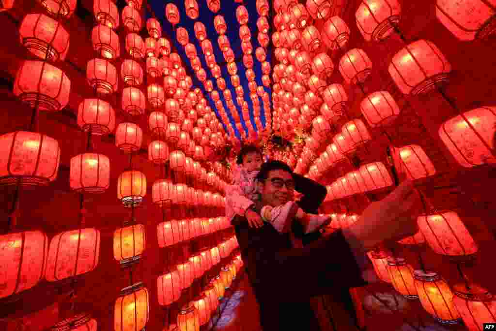 People take photos next to a display of lanterns decorated with lights during the Lantern Festival, which marks the end of the Lunar New Year celebrations in Taiyuan, in northern China&#39;s Shanxi province.
