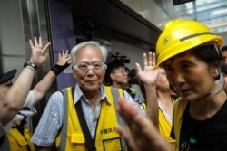 "Grandpa Wong," center left, 85, shields protesters from the police by stepping between them along with other "silver hair" volunteers in the Tung Chung district in Hong Kong, Sept. 7, 2019.