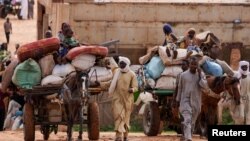 FILE - Chadian cart owners transport belongings of Sudanese people who fled the conflict in Sudan's Darfur region, while crossing the border between Sudan and Chad in Adre, Chad August 4, 2023.