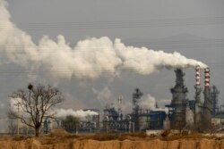 FILE - Smoke and steam rise from a coal processing plant that produces carbon black, an ingredient in steel manufacturing, in Hejin in central China's Shanxi Province, Nov. 28, 2019.