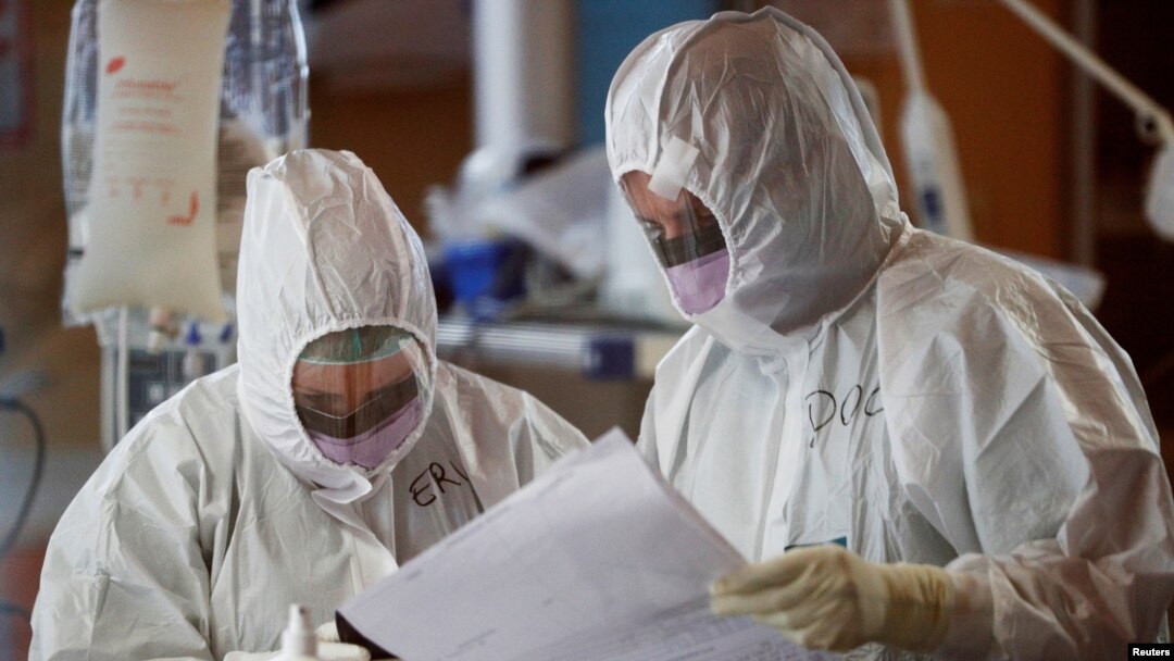 Medical workers in protective suits check a document as they treat patients suffering with coronavirus disease (COVID-19) in an intensive care unit at the Casalpalocco hospital in Rome, March 24, 2020.