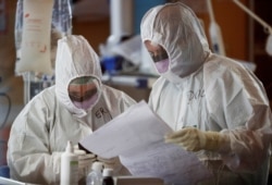 Medical workers in protective suits check a document as they treat patients suffering with coronavirus disease (COVID-19) in an intensive care unit at the Casalpalocco hospital in Rome, March 24, 2020.