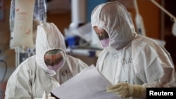 Medical workers in protective suits check a document as they treat patients suffering with coronavirus disease (COVID-19) in an intensive care unit at the Casalpalocco hospital in Rome, March 24, 2020.