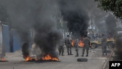 Units of the Mozambican anti-riot police stand among burning barricades during the aftermath of a march called by the presidential candidate of the Optimist Party for the Development of Mozambique in Maputo, on October 21, 2024.