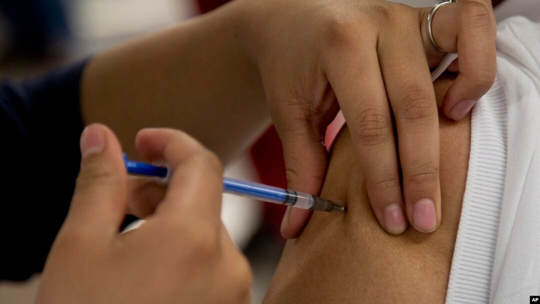 FILE - A woman gets a vaccination from a nurse in Mexico City, Jan. 27, 2014.
