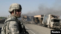 FILE - A U.S. soldier keeps watch at the site where Taliban militants attacked a convoy of supply trucks in Ghazni, Afghanistan, June 24, 2008. Taliban insurgents fired rockets and set dozens of trucks afire on the main highway southeast of Kabul, police said.