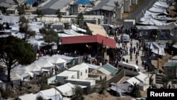 FILE - Refugees and migrants line up for food distribution at the Moria migrant camp on the island of Lesbos, Greece, Oct. 6, 2016. Two people were killed after a fire broke out at the migrant camp late Thursday, a police official said.