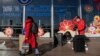 Travelers wearing face masks with their luggage walk through the international flight departure terminal entrance gate at the capital airport in Beijing on Dec. 29, 2022.