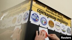 A man posts symbols of parties that will run in the country's March 4 election at the Ministry of the Interior palace in Rome, Italy, Jan. 19, 2018. 