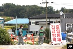 FILE - Quarantine officials stand guard as a precaution against African swine fever near a pig farm in Paju, South Korea, Sept. 20, 2019.