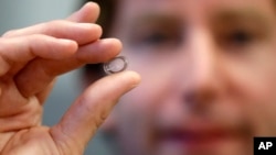 FILE - Brian Otis, Google X project lead, holds a contact lens Google is testing to explore tear glucose in Mountain View, California, Jan. 15, 2014.