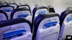 FILE - Safety cards in seat backs are seen on an Alaska Airlines Boeing 737 Max 9 aircraft at Seattle-Tacoma International Airport Jan. 10, 2024. The Justice Department says Boeing violated a settlement that let the company avoid criminal prosecution after two deadly crashes. 