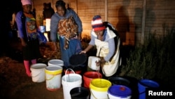FILE - Residents collect water at night from an electric-powered well, as the country faces 18-hour daily power cuts, in a suburb of Harare, Zimbabwe, July 30, 2019.