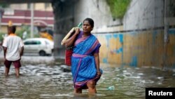Warga harus berjalan melalui jalanan yang tergenang air akibat hujan lebat di Chennai, India, 2 Desember 2019. Sedikitnya 15 tewas akibat tertimpa tembok yang roboh akibat hujan lebat di Cimbatore, India Selatan. 