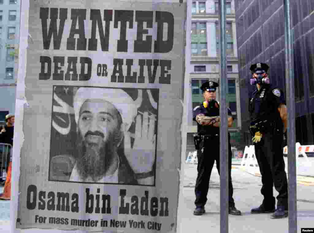 Polisi New York berdiri dekat poster pencarian Osama bin Laden di distrik finansial New York, 18 September 2001. (Reuters/Russell Boyce)