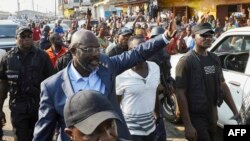 George Weah, candidat à la présidentielle libérienne de la Coalition pour le changement démocratique, au centre, salue la foule en plein Monrovia le 6 décembre 2017. / AFP PHOTO / Hugh Kinsella Cunningham