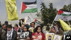 Palestinians hold flags and photographs during a protest in solidarity with Adnan, and for the release of Palestinian prisoners held in Israeli prisons, in the West Bank city of Nablus, February 8, 2012.