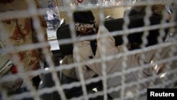 A blindfolded man sits in a Pakistani rangers' vehicle after being arrested for inciting unrest in a residential area in Karachi, December 26, 2012.