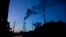 FILE - Traffic moves as smoke emits from the chimney of a factory on the outskirts of Gauhati, India, Sunday, Oct. 2, 2016. 