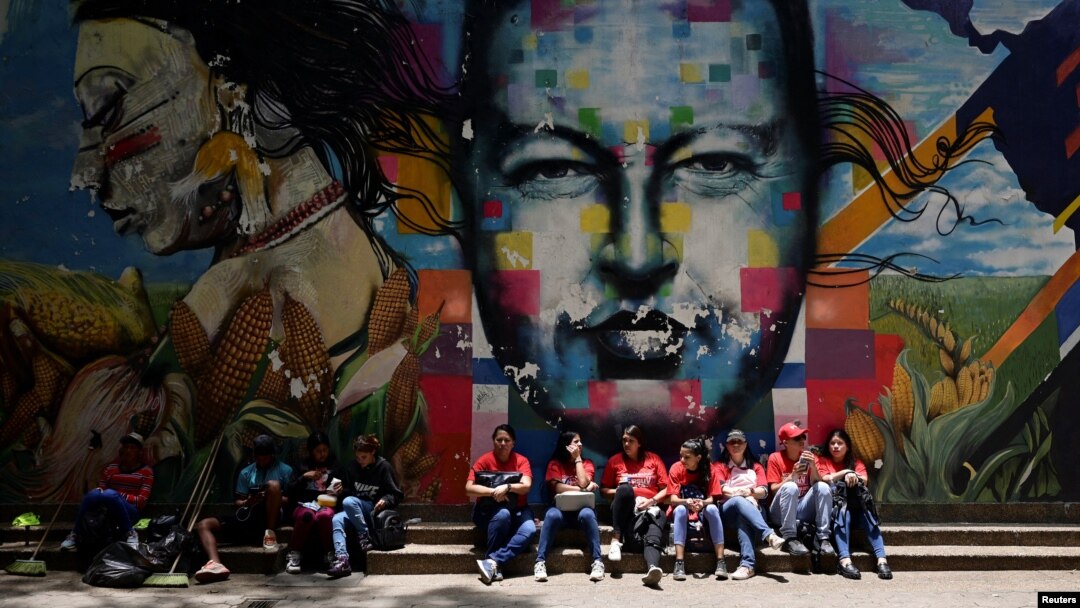 Simpatizantes del presidente Nicolás Maduro descansan bajo una pintura del rostro del expresidente Hugo Chávez, en Caracas, el 22 de agosto de 2024. Estados Unidos anunció este jueves sanciones contra 16 funcionarios del gobierno.