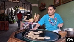 Una trabajadora del restaurante Fonda de la Calle Real hace tortillas para los platos de la casa en la hornilla a leña instalada en las puertas del establecimiento, donde los comensales pueden deleitarse con los platos típicos de la cocina antigüeña. [Foto: Tomás Guevara, VOA]