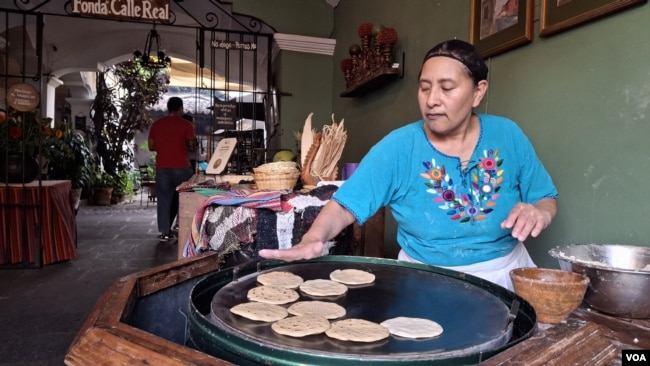 Una trabajadora del restaurante Fonda de la Calle Real hace tortillas para los platos de la casa en la hornilla a leña instalada en las puertas del establecimiento, donde los comensales pueden deleitarse con los platos típicos de la cocina antigüeña. [Foto: Tomás Guevara, VOA]